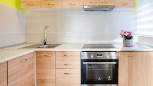 A modern kitchen with wooden cabinets, a stainless steel dishwasher, and an oven. - Delightful Apartment in Vir With Garden (Vir)