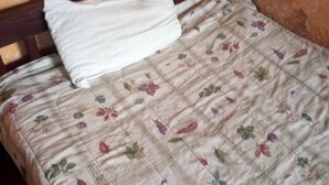 Een bed met een bloemenprint deken en een wit kussen.