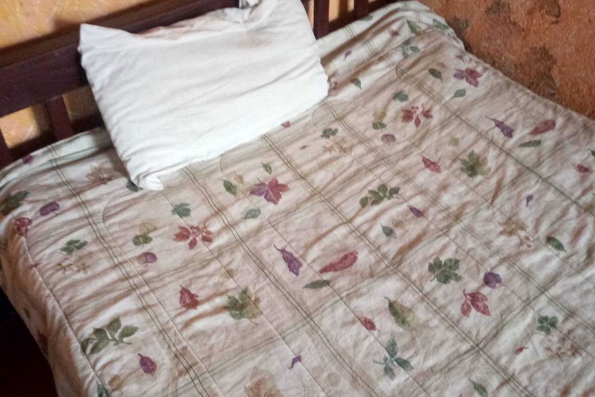 Un lit avec une couvre-lit à motifs floraux et un oreiller blanc.