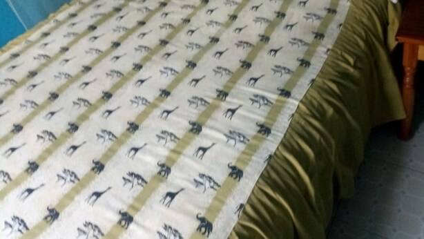 Een bed met een bedsprei met patroon, witte kussens en een houten hoofdbord.