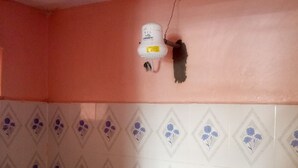 Een badkamer met een roze muur, betegelde vloer en een witte douchehoek.