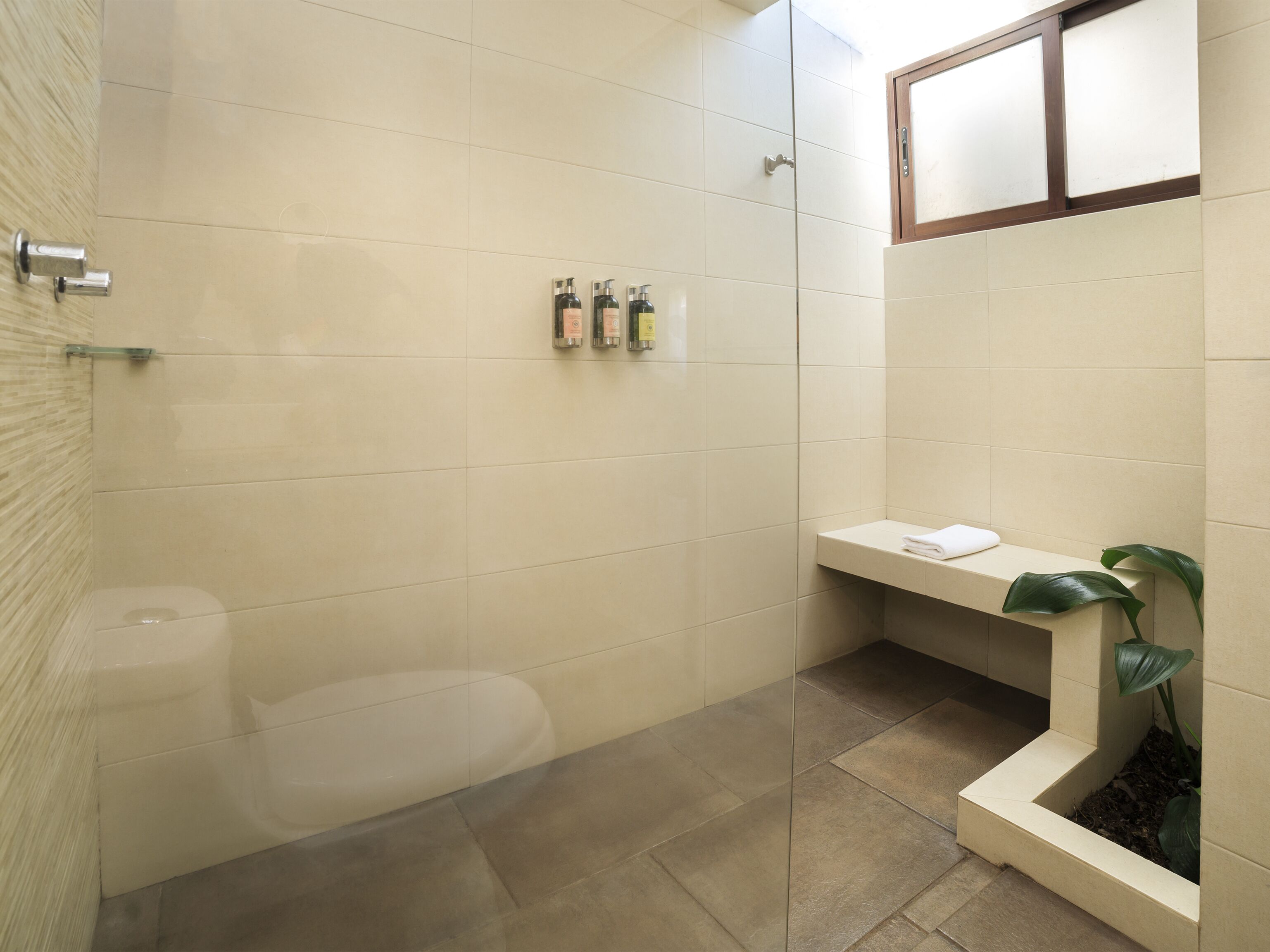 A modern bathroom with a toilet, a shower area, and a small shelf with toiletries.