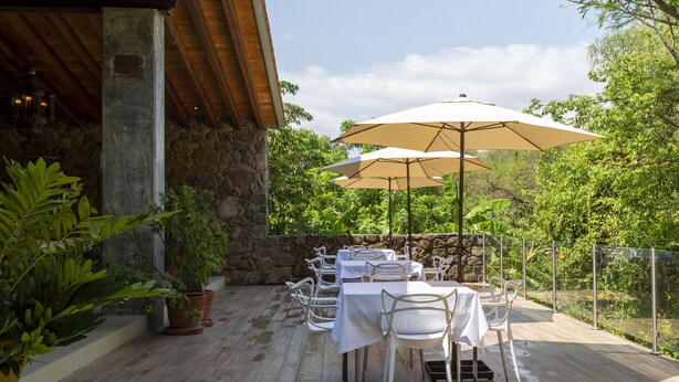 An outdoor patio with tables and chairs, surrounded by stone walls and potted plants. - Hotel Amate del Rio (Malinalco)