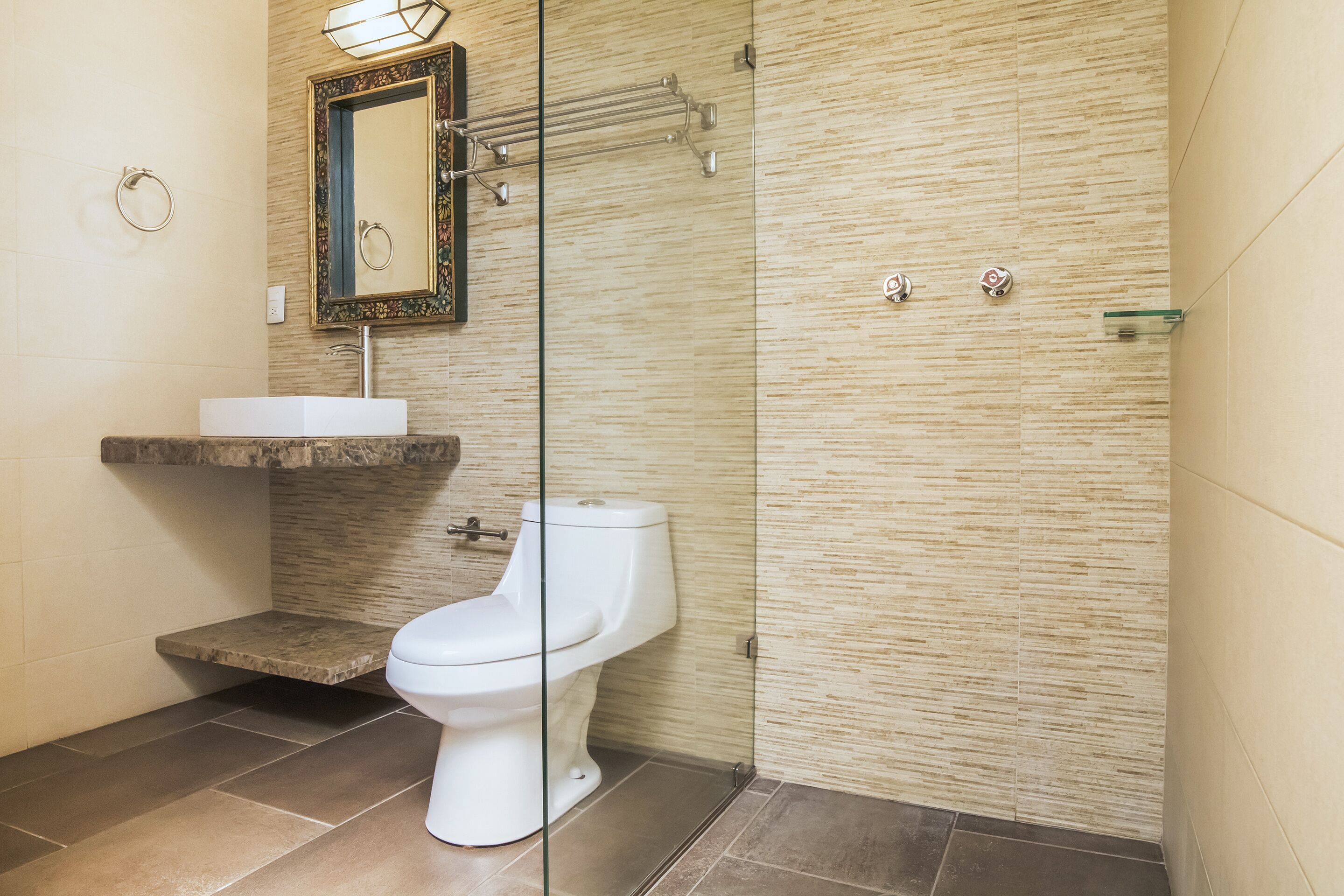 Une salle de bain moderne équipée de toilettes, d’un lavabo et d’une douche à parois en verre.