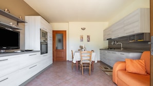 Una cocina compacta con electrodomésticos modernos, un comedor con mesa y sillas, y un sofá.