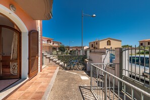 Zona residencial com varanda, uma bicicleta e um carro estacionado ao fundo.