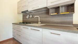 Una cocina moderna con estufa integrada, pileta y armarios superiores.