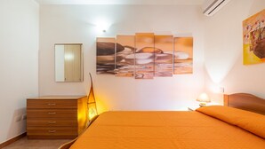 Un dormitorio con cama, cómoda, espejo en la pared y un cuadro.