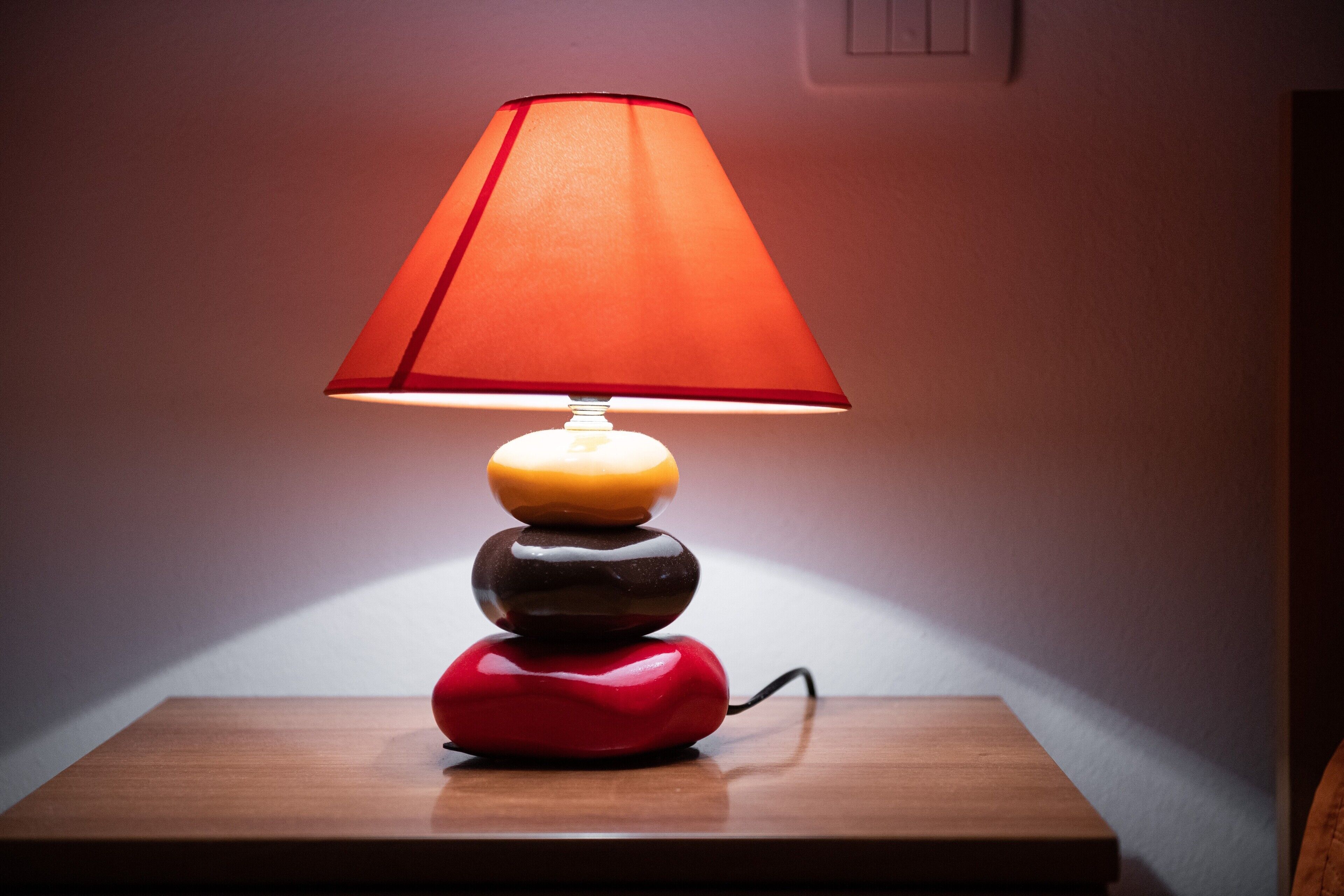En lampe med rød skærm på en træoverflade.