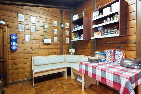A cozy kitchen with a wooden bench, a table with a checkered tablecloth, and shelves with kitchen items. - Charming "Casa Rural" with Sea View, Mountain View, Wi-Fi, Garden, Terrace & Pool (Arafo)