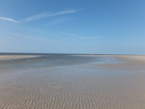A beach with sand patterns and a clear sky.