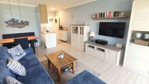 Un salon moderne comprenant un canapé, une table basse, un téléviseur et un coin cuisine.