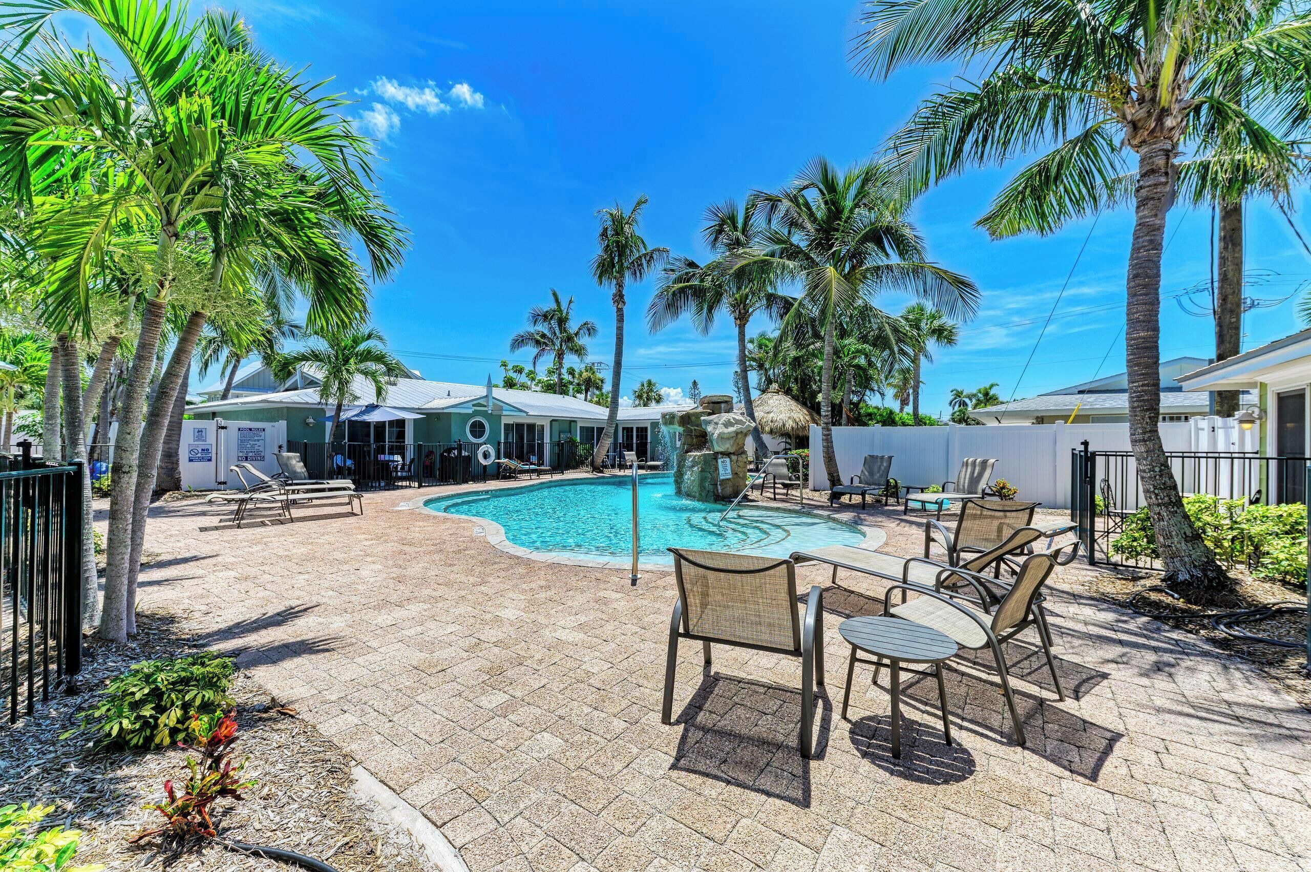 A pool area with lounge chairs and palm trees.