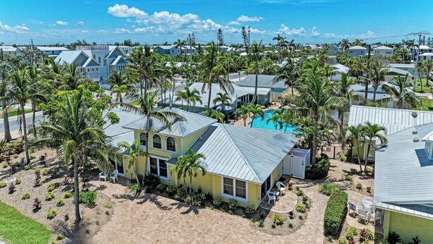Un quartier résidentiel avec des maisons, des palmiers et une piscine.