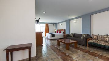 Una habitación de hotel con cama, sofá, mesa de centro y escritorio.