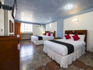 Una habitación de hotel con dos camas, un escritorio de madera y una ventana con cortinas.
