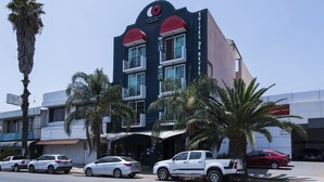 Um hotel com design moderno, apresentando um esquema de cores marcante em vermelho e azul, várias varandas e uma entrada visível.