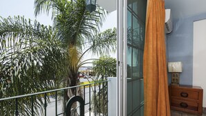 Varanda com vista para palmeiras e uma rua.