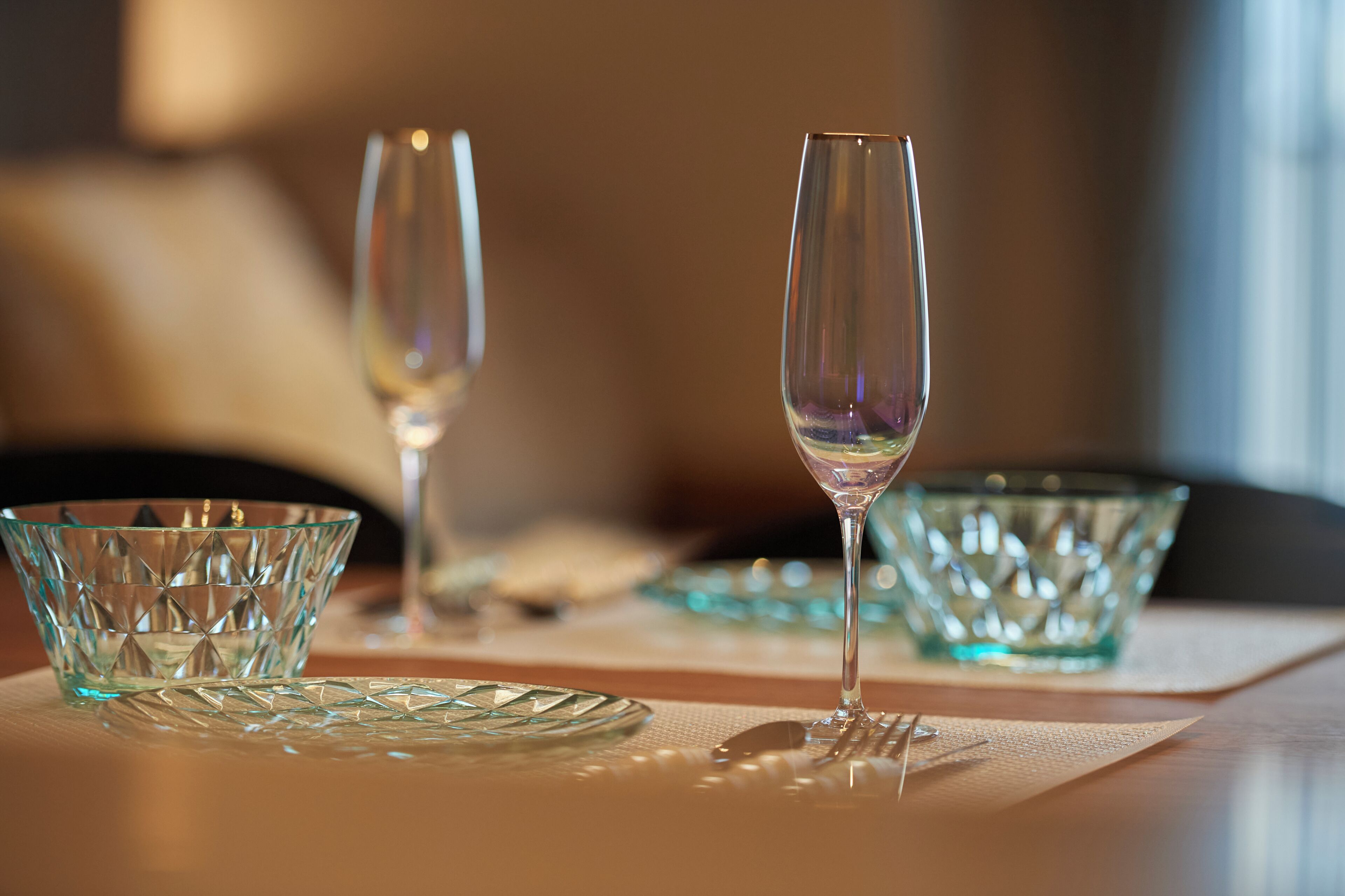 Una mesa con dos copas de cristal transparente y un bol de cristal texturizado.