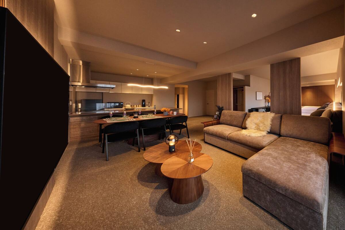 Una habitación de hotel moderna con comedor, un sofá y una mesa de centro.