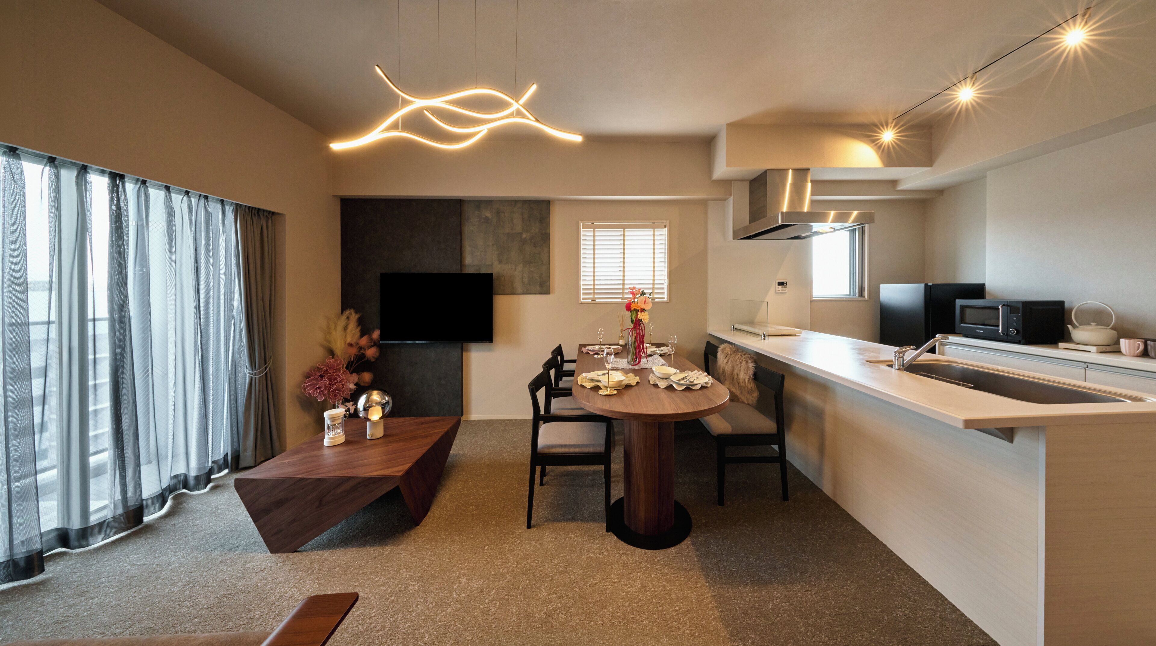 A modern kitchen with a dining area, a flat-screen TV mounted on the wall, and a built-in microwave.