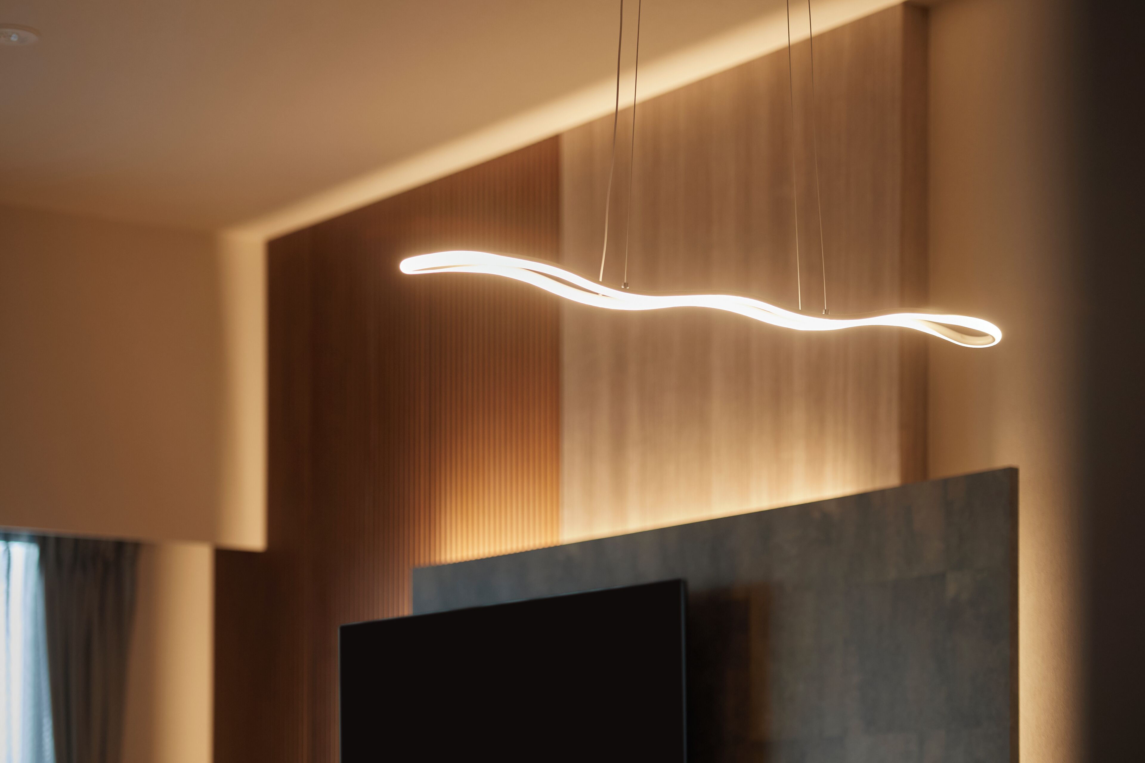 Un interior moderno con una lámpara de techo original, un televisor de pantalla plana y paneles de madera.