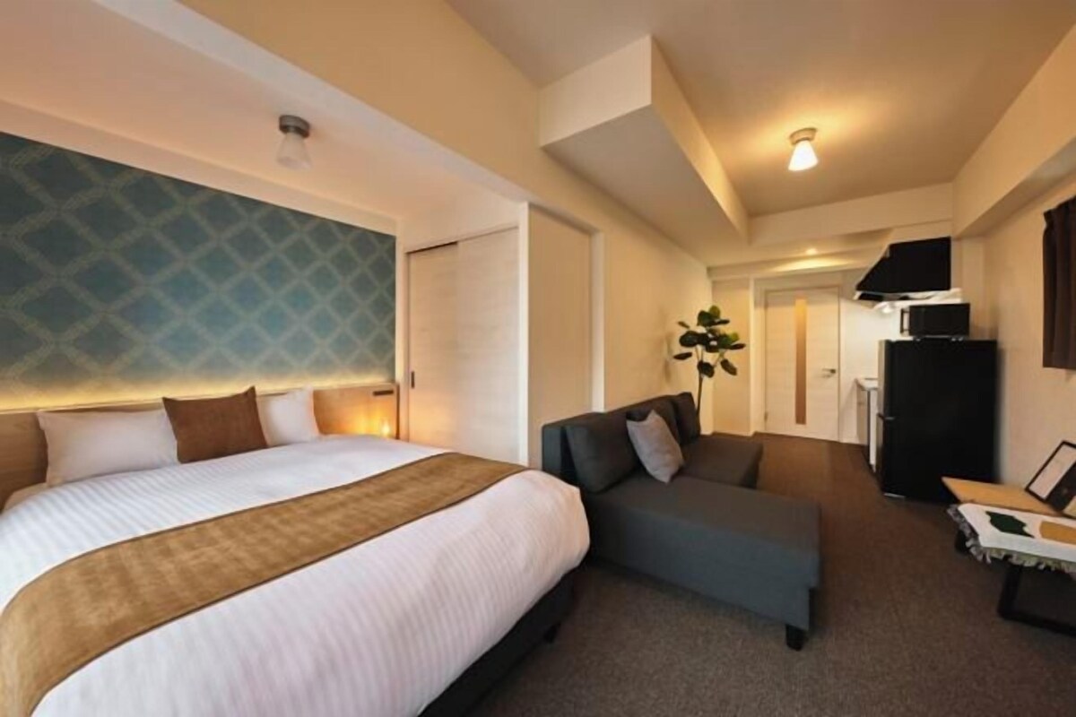 Ein Hotelzimmer mit einem großen Bett, einer Couch, einem Schreibtisch und einem Fernseher.