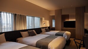 Une chambre d’hôtel avec trois lits, un téléviseur à écran plat et un bureau avec une chaise.