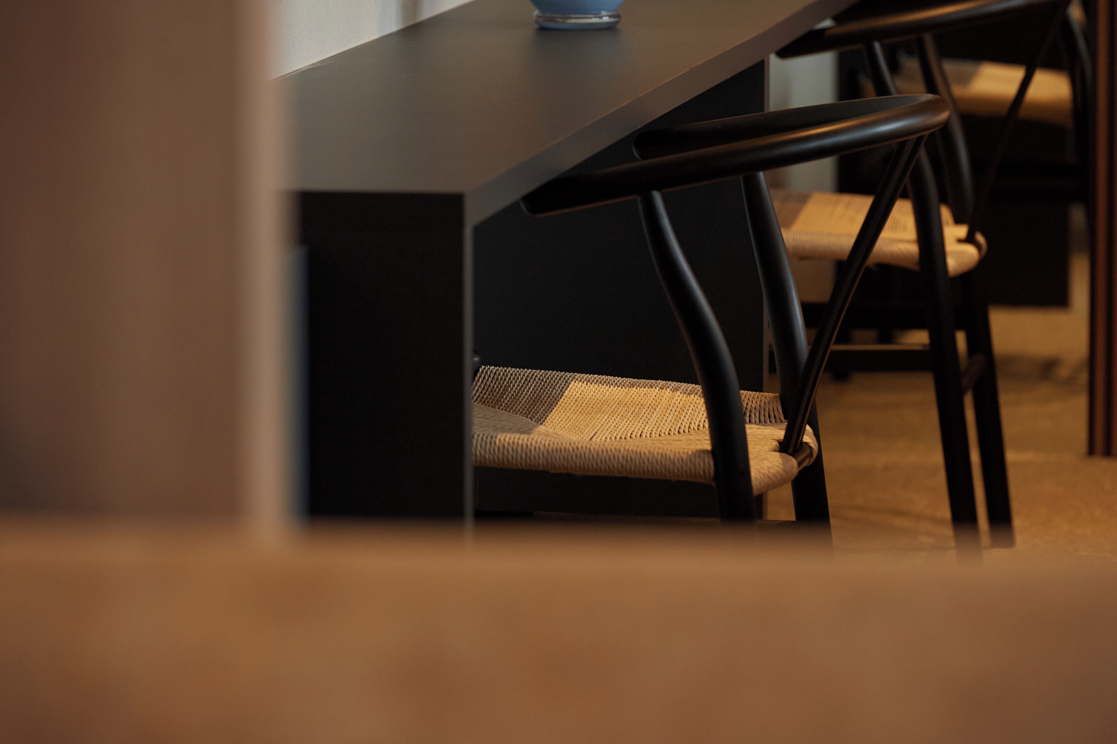 Ein modernes Zimmer mit einem dunklen Holztisch und einem gewebten Stuhl.