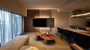Un salon moderne doté d’un téléviseur à écran plat, d’un coin repas avec une longue table et d’un canapé.