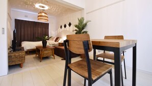 Ein modernes Wohnzimmer mit Essbereich, ausgestattet mit einem Holztisch, Stühlen, einer Couch und einem Fernseher.