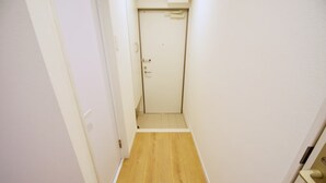 Ein schmaler Korridor mit Holzdielen und weißen Wänden.