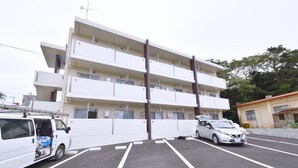 Ein mehrstöckiges Gebäude mit Parkplatz davor.