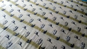 Een bed met een bedspreide met een patroon van vogelmotieven.