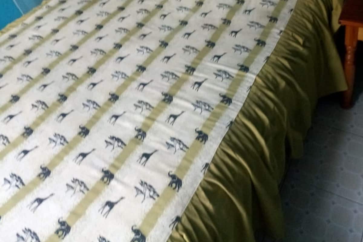 A bed with a patterned bedspread, white pillows, and a wooden headboard.