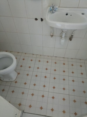 A bathroom with a toilet, a sink, and patterned floor tiles.