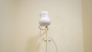 Een witte douchekop bevestigd aan een muur, verbonden met een witte leiding.