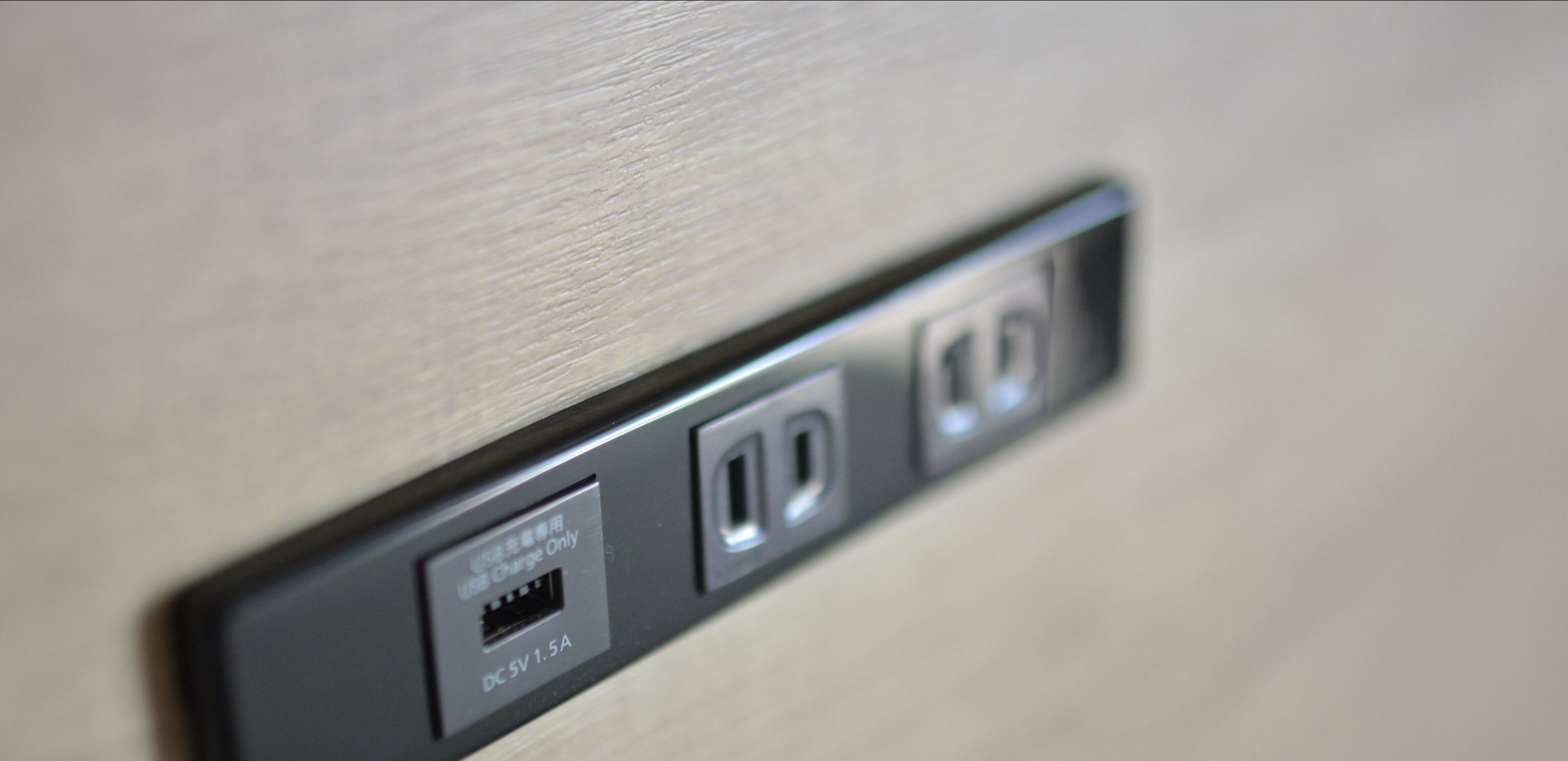 A close-up of a wall-mounted power outlet with USB and DC charging ports.