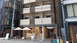 A multi-story hotel with a modern design, featuring balconies, a ground-level café, and visible signage for the hotel. - TAKUTO HOTEL Shinsaibashi (Osaka)
