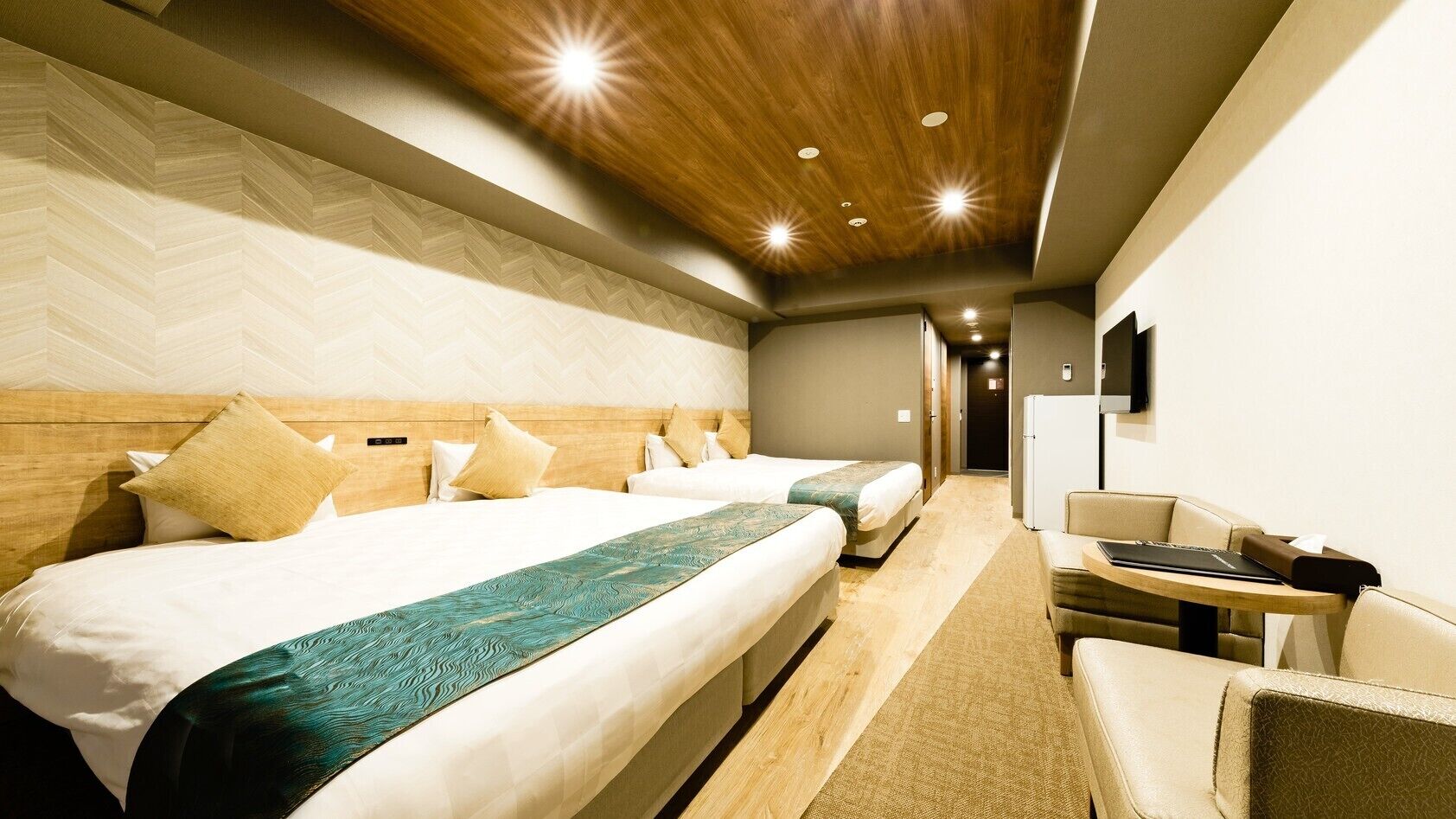Une chambre d’hôtel avec un grand lit, un lit plus petit, un bureau et une chaise.