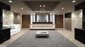 A modern lobby with a reception desk, a white sofa, a marble coffee table, and a patterned carpet. - TAKUTO HOTEL Shinsaibashi (Osaka)
