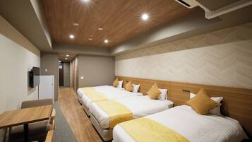 A hotel room with two beds, a desk, a television, and a corridor leading to another room.