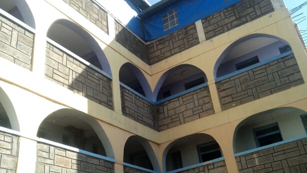A multi-level building with a central courtyard, featuring arched balconies and a mix of stone and painted walls.