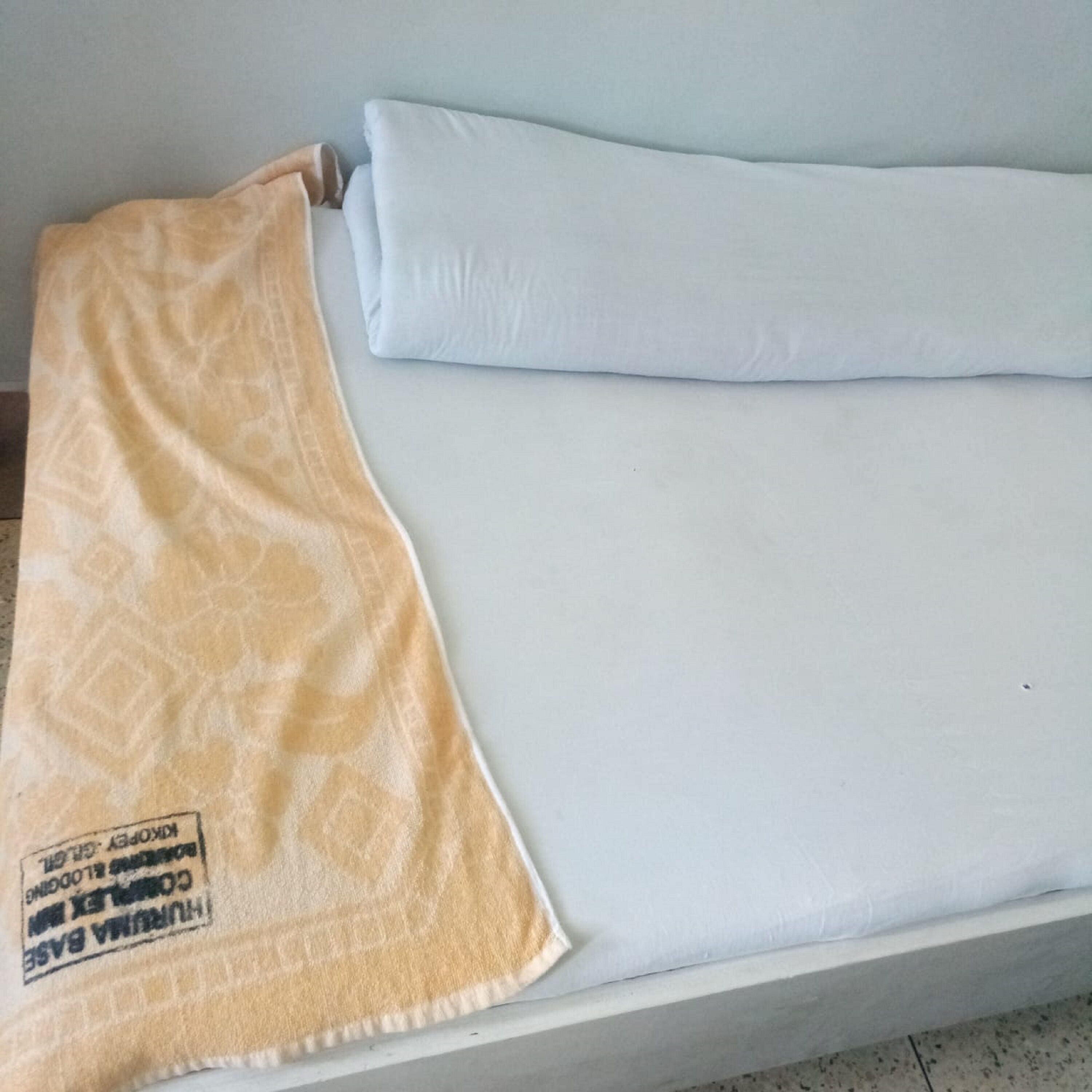 A bed with a white mattress and a patterned blanket.