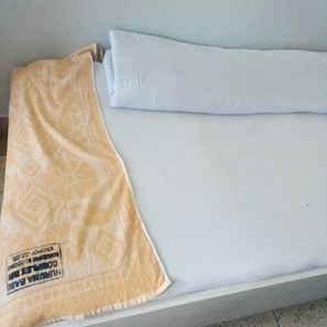 A bed with a white mattress and a patterned blanket. - Huruma Lodge (Gilgil)