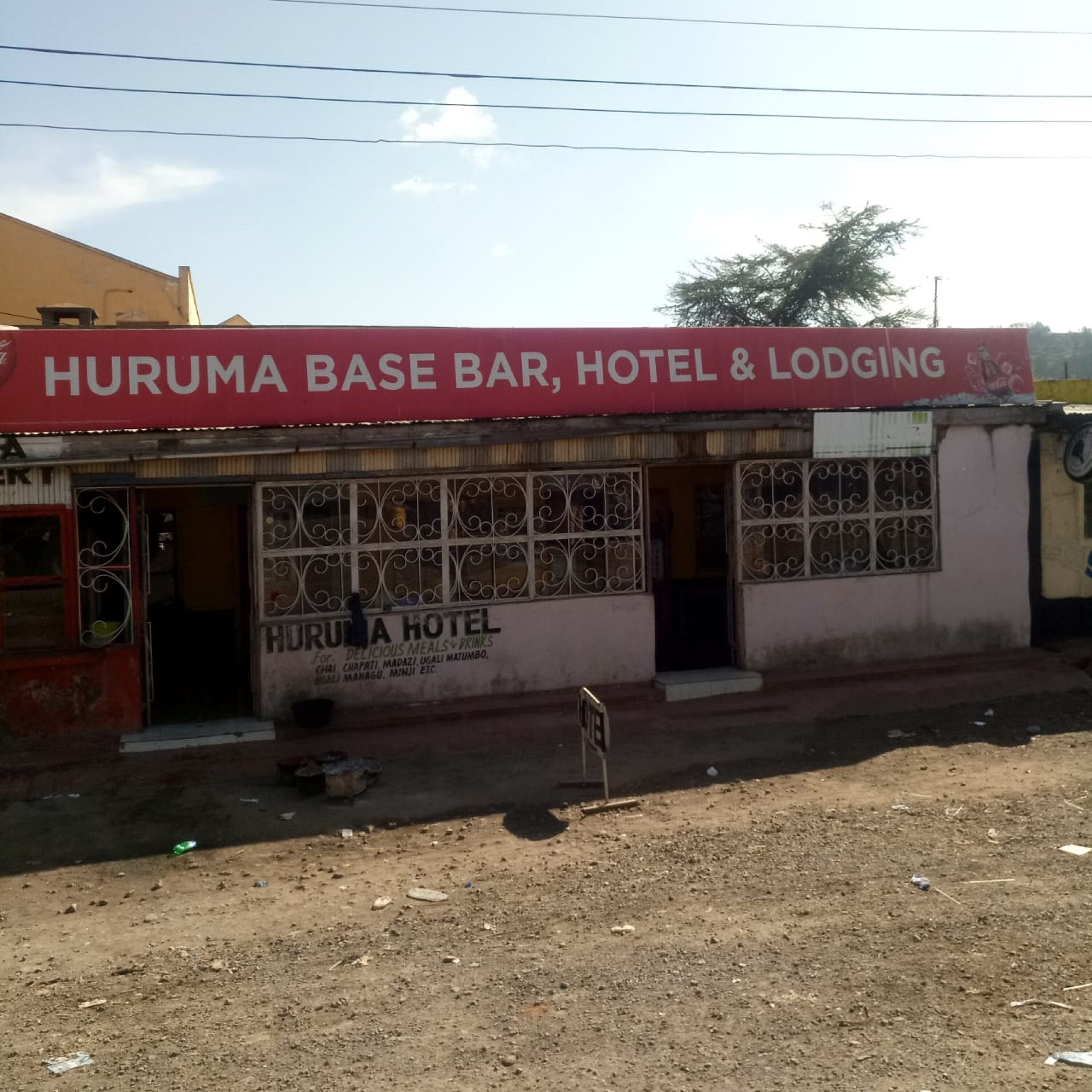 Un bâtiment sur lequel on peut lire l’inscription suivante : « HURUMA BASE BAR, HÔTEL ET CHAMBRES ».