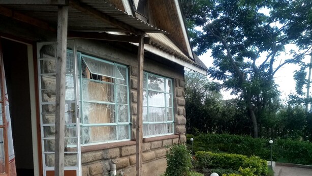 A stone house with a porch, a small garden with shrubs and a pathway. - Hudson's Sports Bar and Restaurant (Nakuru)