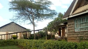A residential area with a grassy lawn, a wooden fence, and a stone building with a window. - Hudson's Sports Bar and Restaurant (Nakuru)