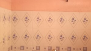 Une pièce avec un mur orné de motifs, un luminaire au plafond et une porte dotée d’une poignée.