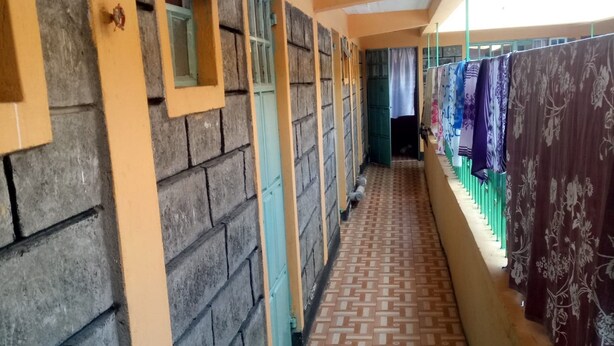 Un couloir avec un sol à motifs, un mur en briques et une fenêtre avec un rideau.
